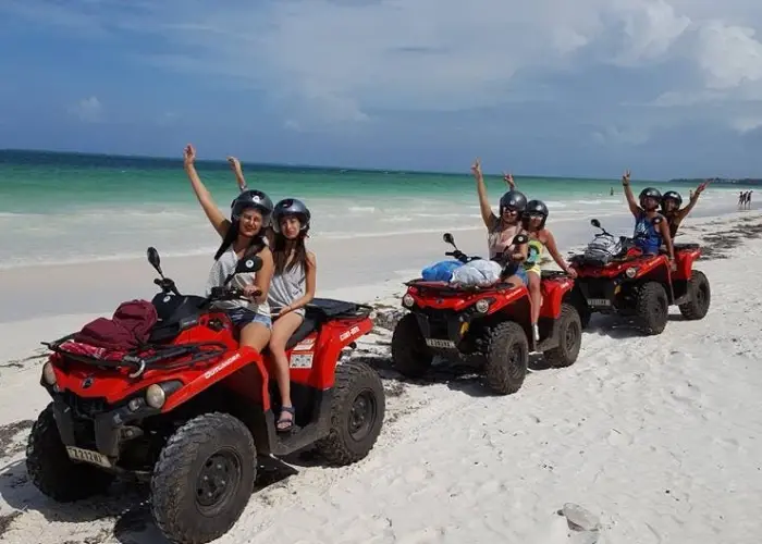 a group of tourist enjoying a quad bike ride on the beach in zanzibar
